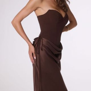 Model wearing the Espresso Remi Gown, a strapless satin formal dress featuring a structured corset bodice, draped hip detailing, lace-up back and fitted floor-length skirt.