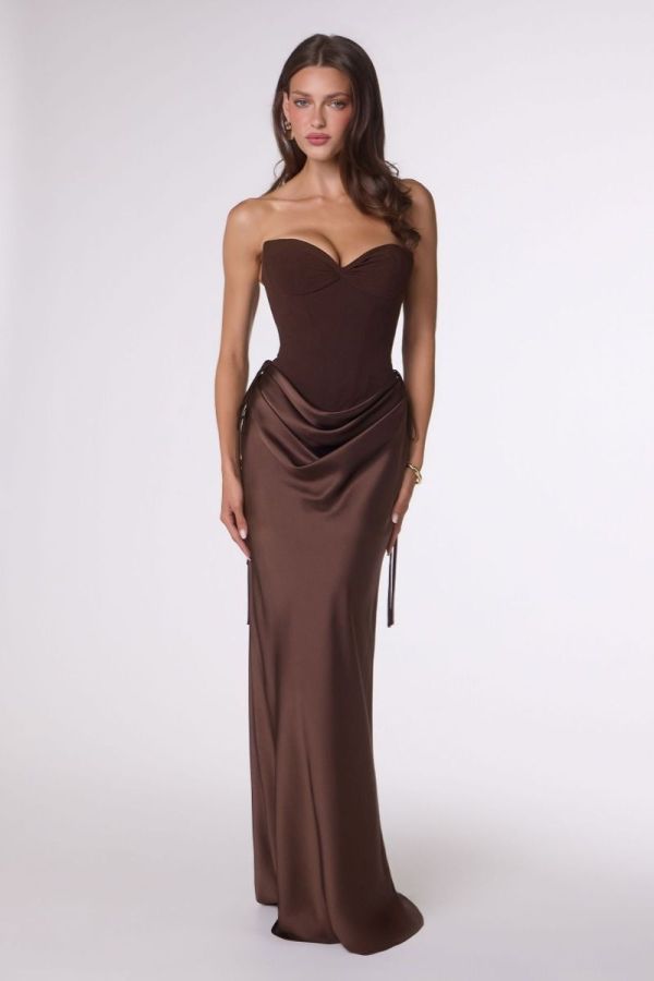 Model wearing the Espresso Remi Gown, a strapless satin formal dress featuring a structured corset bodice, draped hip detailing, lace-up back and fitted floor-length skirt.